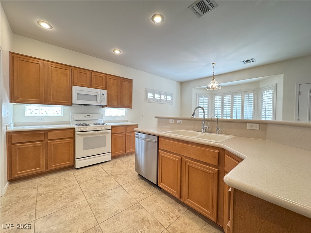 3013 Hartsville Road Henderson, NV 89052 - Photo 36 of 43 Kitchen featuring white appliances, visible vents, brown cabinets, and a sink