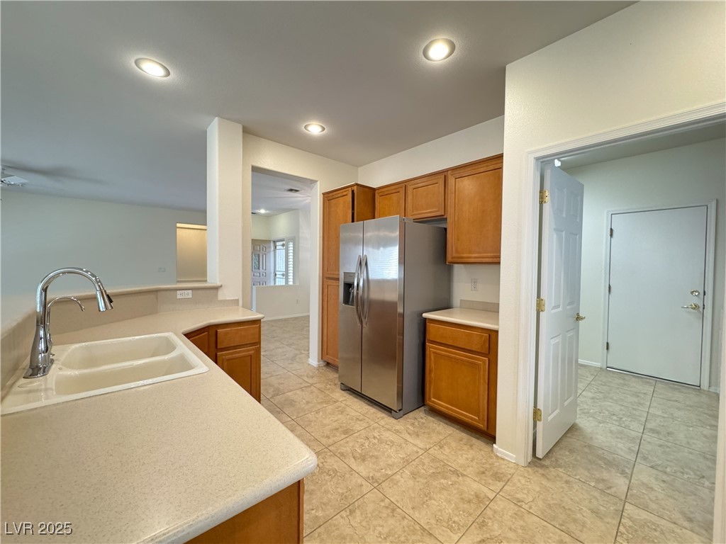 3013 Hartsville Road Henderson, NV 89052 - Photo 39 of 43 Kitchen featuring light countertops, stainless steel fridge, a sink, and brown cabinets