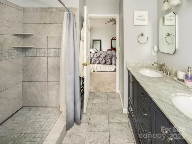 a bathroom with a granite countertop sink a mirror and shower