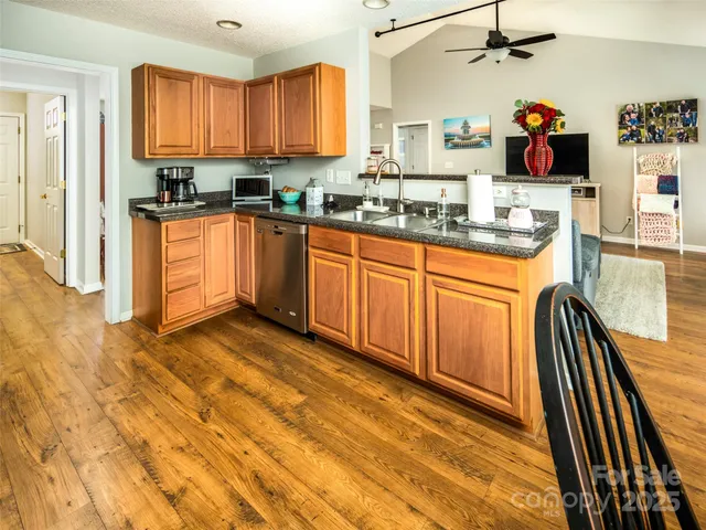 a kitchen with stainless steel appliances granite countertop a sink dishwasher and cabinets with wooden floor