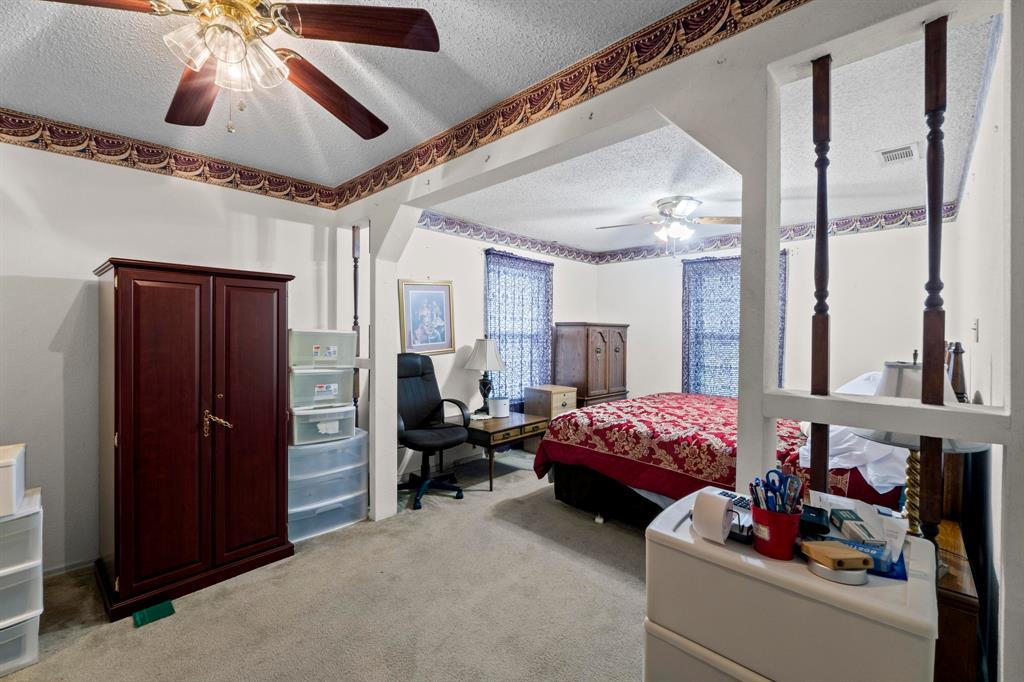 4604 Munson Street Austin, TX 78721 - Photo 12 of 18 Bedroom featuring a textured ceiling, light carpet, and a ceiling fan