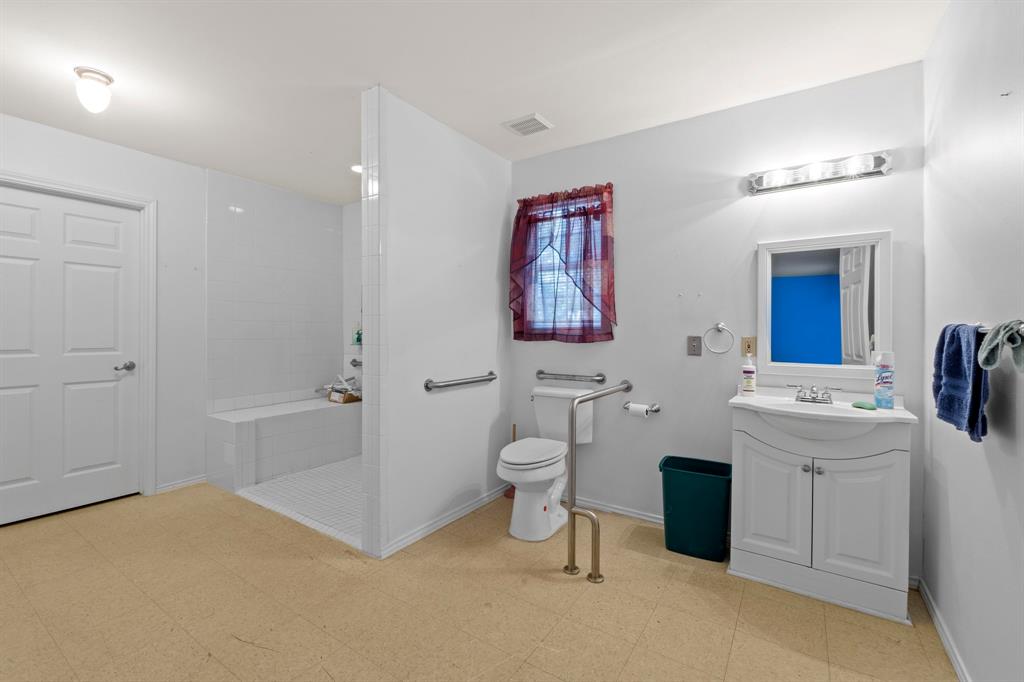 4604 Munson Street Austin, TX 78721 - Photo 16 of 18 Bathroom with light flooring, vanity, and a walk in shower