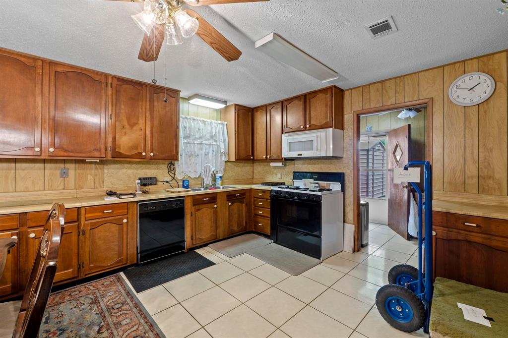 4604 Munson Street Austin, TX 78721 - Photo 4 of 18 Kitchen with wood finish cabinets, a ceiling fan, light countertops, and a textured ceiling