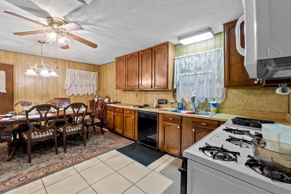 4604 Munson Street Austin, TX 78721 - Photo 5 of 18 Kitchen with white appliances, light countertops, wood finish cabinets, wood walls, and a textured ceiling