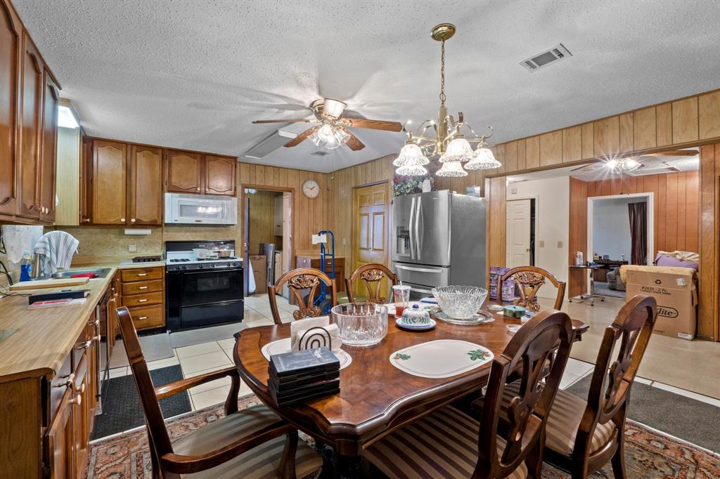 4604 Munson Street Austin, TX 78721 - Photo 6 of 18 Dining area featuring a textured ceiling, a ceiling fan, wooden walls, and hanging lights