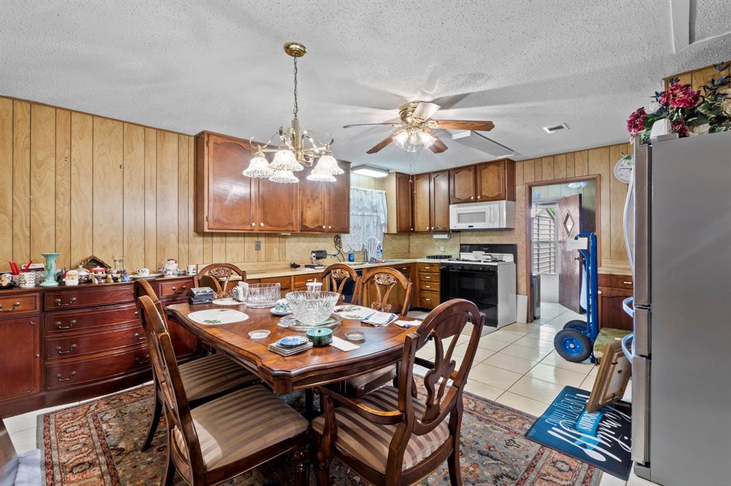 4604 Munson Street Austin, TX 78721 - Photo 7 of 18 Dining room with wood walls, a textured ceiling, light tile patterned floors, hanging lights, and a ceiling fan