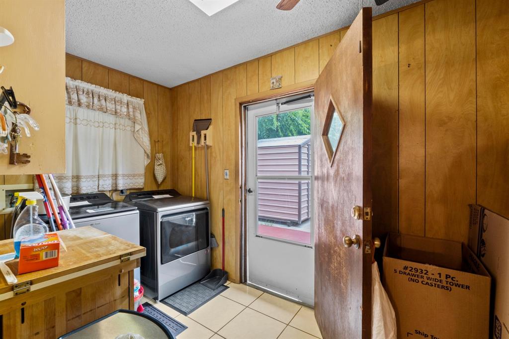 4604 Munson Street Austin, TX 78721 - Photo 8 of 18 Laundry room featuring a textured ceiling, wood walls, light tile patterned flooring, independent washer and dryer, and a ceiling fan
