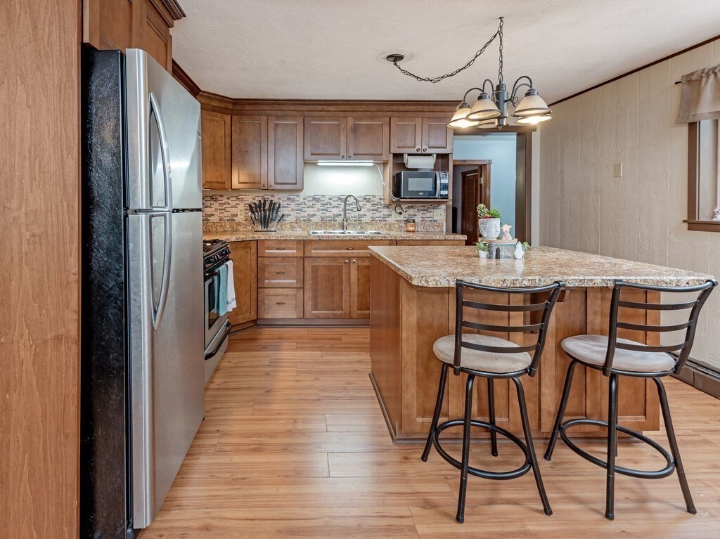 428 Keys Road Warren, MA 01585 - Photo 4 of 26 a kitchen with stainless steel appliances kitchen island granite countertop a refrigerator a stove a microwave oven with a dining table and chairs