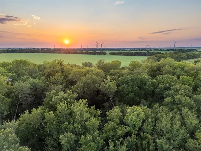 a view of a lush green outdoor space with a swimming pool and valleys in the background