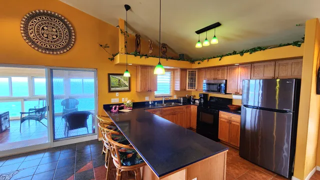 a kitchen with stainless steel appliances granite countertop a refrigerator a stove top oven a dining table and chairs with wooden floor