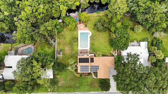 an aerial view of a house with a yard and large trees