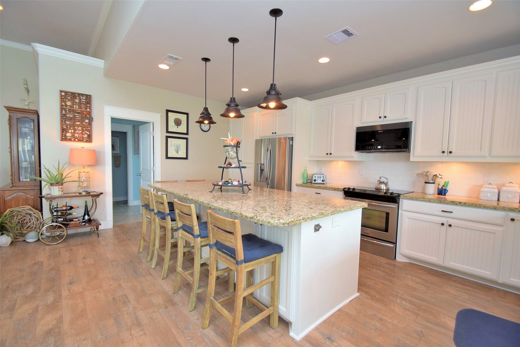 956 South Redfish Crystal Beach, TX 77650 - Photo 9 of 20 a kitchen with stainless steel appliances kitchen island granite countertop a stove a sink a dining table and chairs with wooden floor