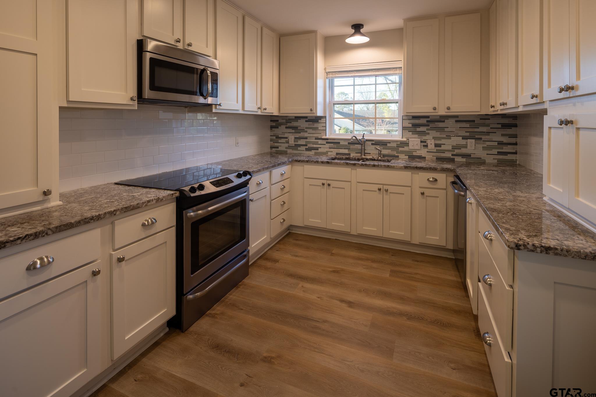 2802 Pollard Drive Tyler, TX 75701 - Photo 7 of 38 a kitchen with stainless steel appliances granite countertop a stove a sink and white cabinets