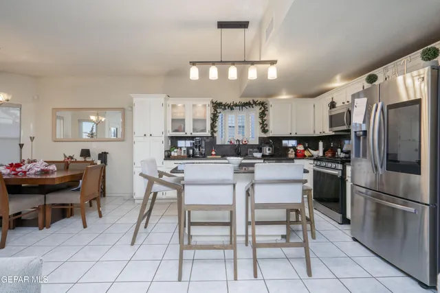 a kitchen with stainless steel appliances a table chairs refrigerator and cabinets