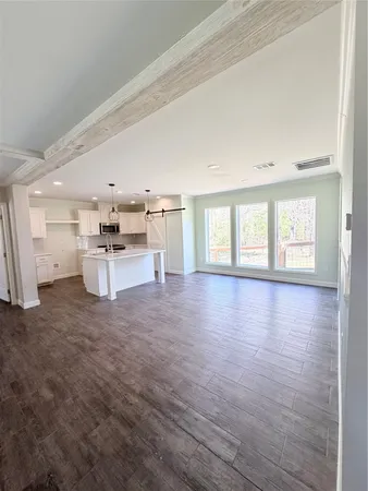 an empty room with windows and kitchen view