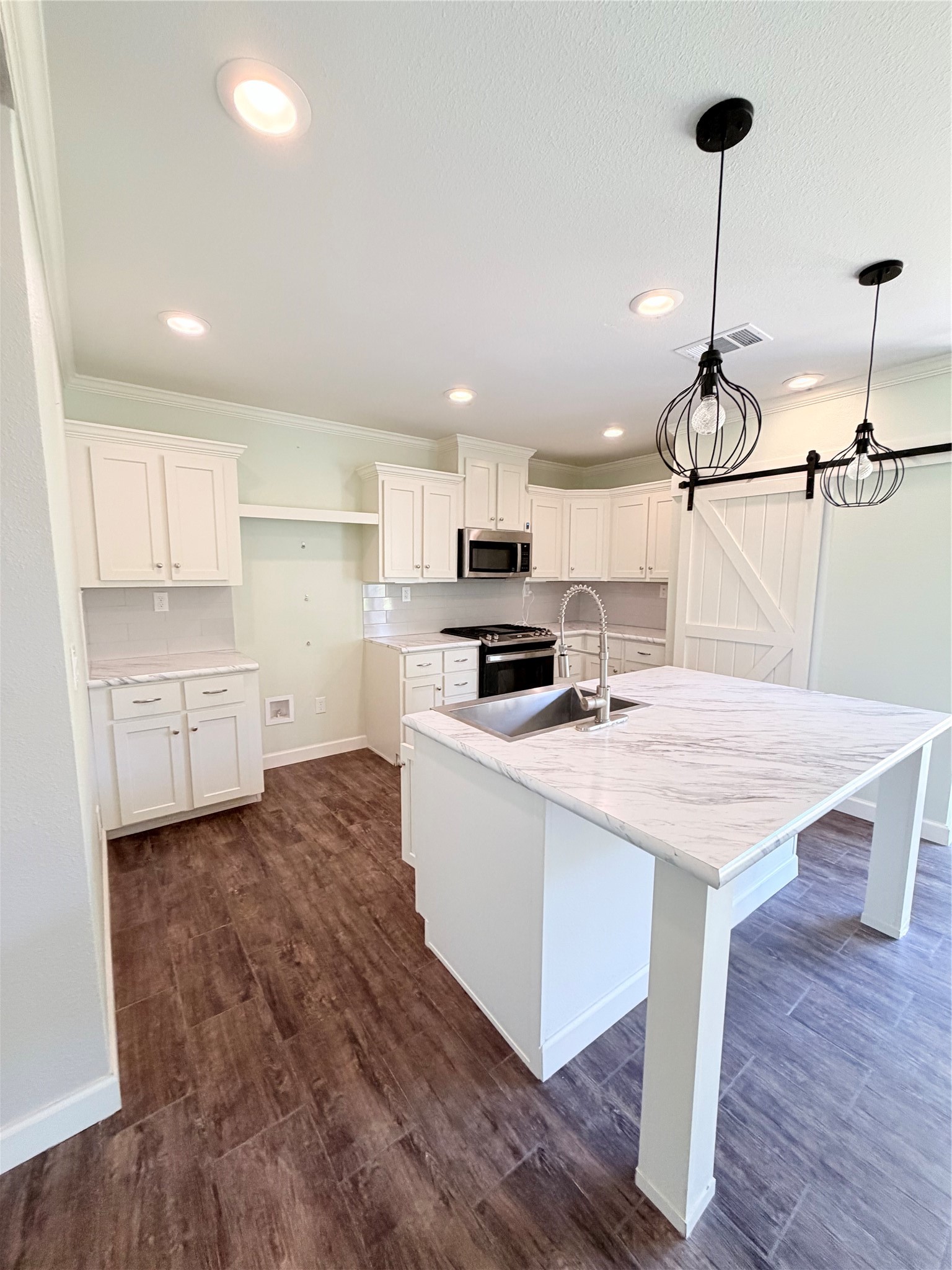 59 Forgotten Road Richards, TX 77873 - Photo 4 of 21 a kitchen with kitchen island a stove a sink a refrigerator and white cabinets with wooden floor