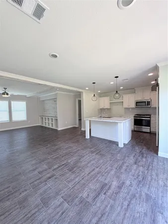 a large white kitchen with kitchen island a sink dishwasher and a stove with wooden floor
