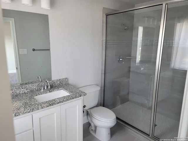 a bathroom with a granite countertop sink toilet and shower