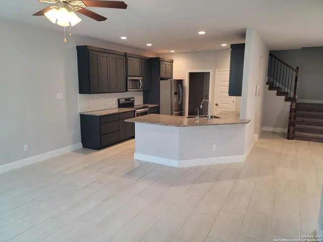 a large kitchen with stainless steel appliances a large counter top and a stove