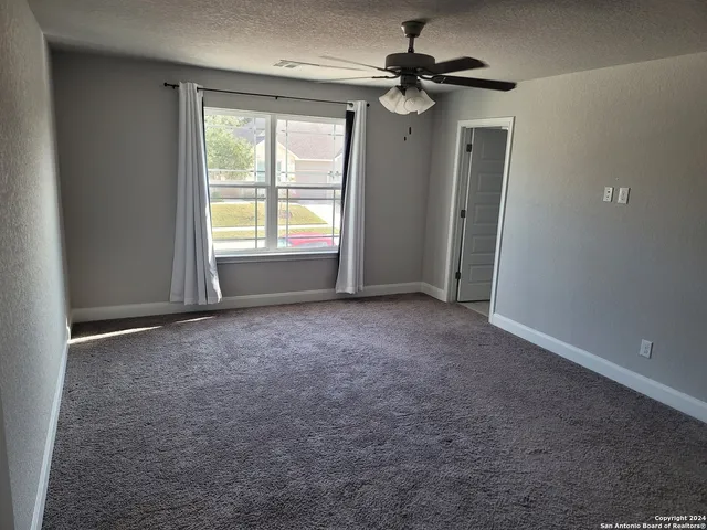 an empty room with windows and fan