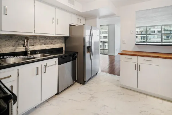 a kitchen with granite countertop a refrigerator sink and cabinets