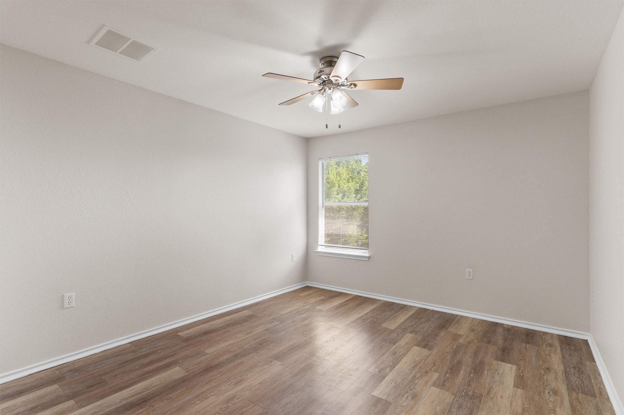 5825 Silver Screen Drive Austin, TX 78747 - Photo 19 of 40 A well-lit bedroom with durable wood flooring and a refreshing ceiling fan.