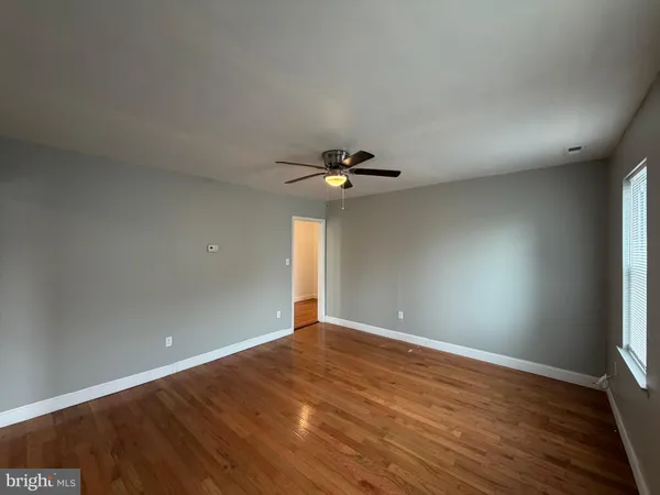 a view of an empty room with window and chandelier fan