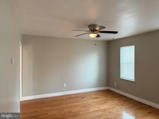 a view of an empty room with window and wooden floor