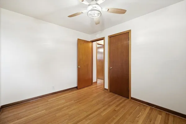 an empty room with wooden floor and fan