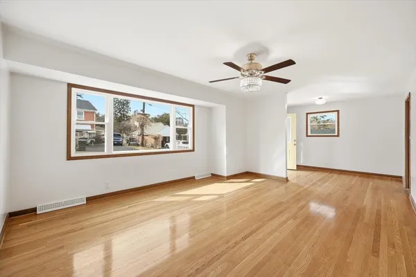 a view of an empty room with a window and wooden floor