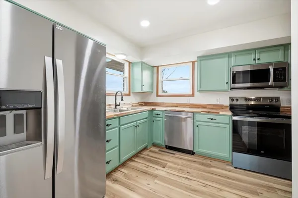 a kitchen with stainless steel appliances granite countertop a refrigerator a stove and a sink