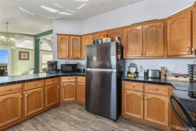 a kitchen with stainless steel appliances granite countertop a refrigerator a sink dishwasher and wooden cabinets with wooden floor