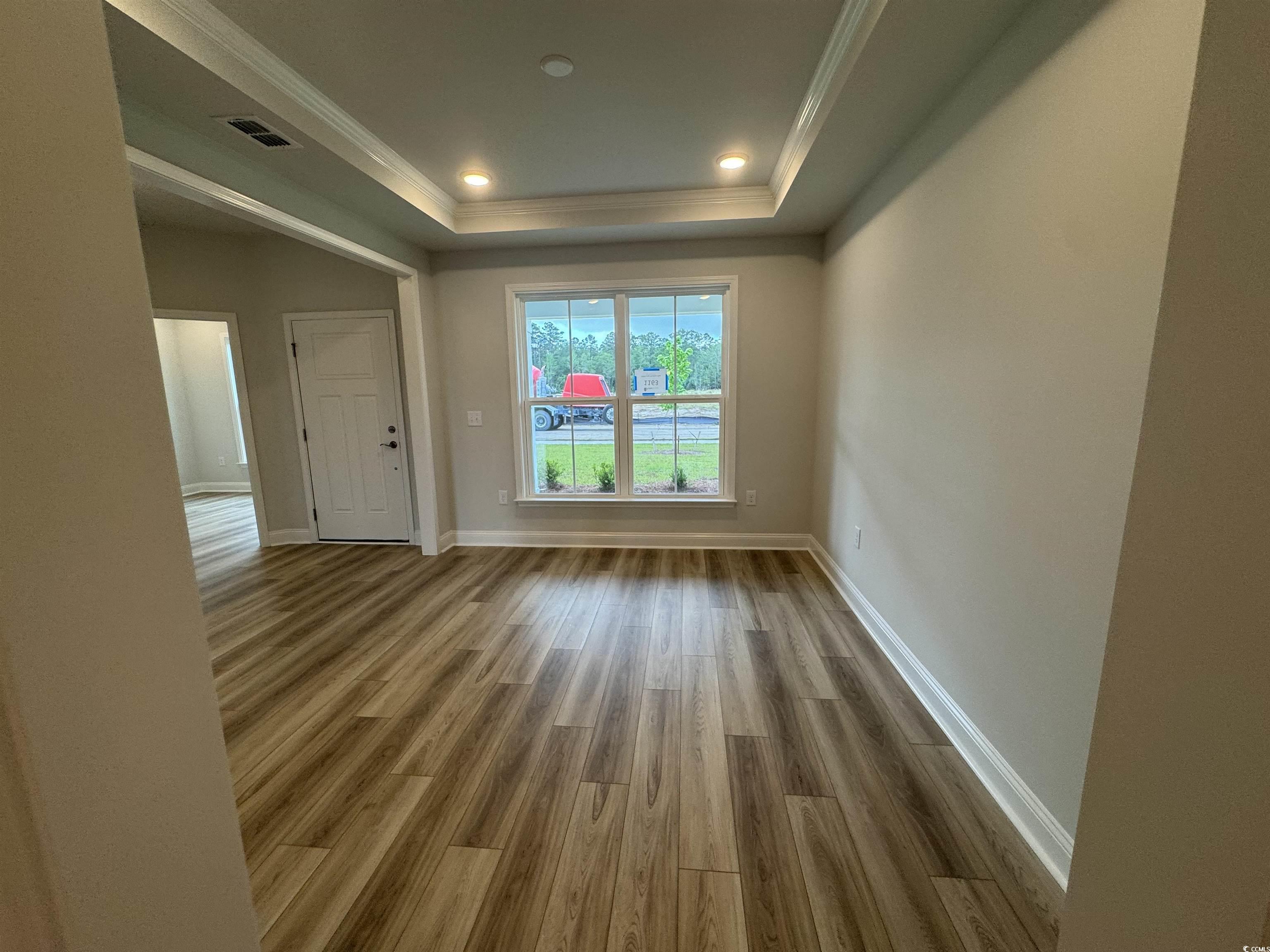9409 Long Meadow Way Longs, SC 29568 - Photo 7 of 17 Empty room with a raised ceiling, wood finished fl