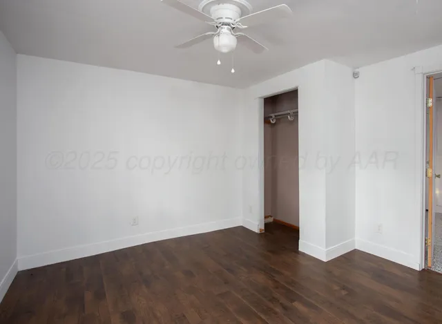 an empty room with wooden floor and a ceiling fan