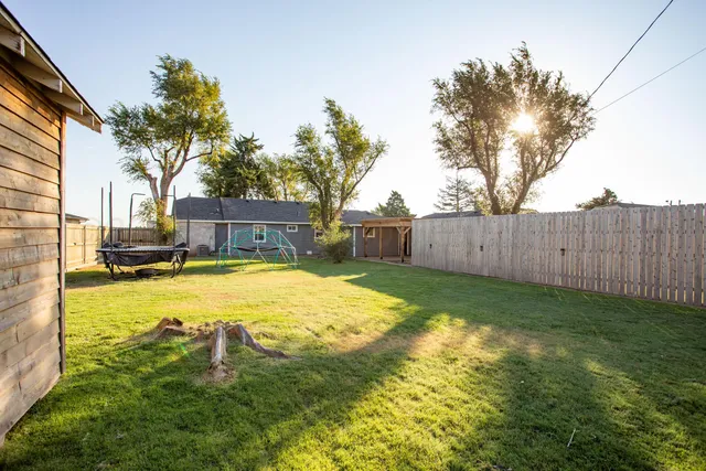 a swimming pool with yard and trees in the background
