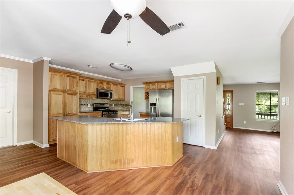 a view of a kitchen with kitchen island wooden floors stainless steel appliances