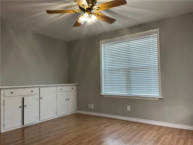 an empty room with wooden floor closet and windows