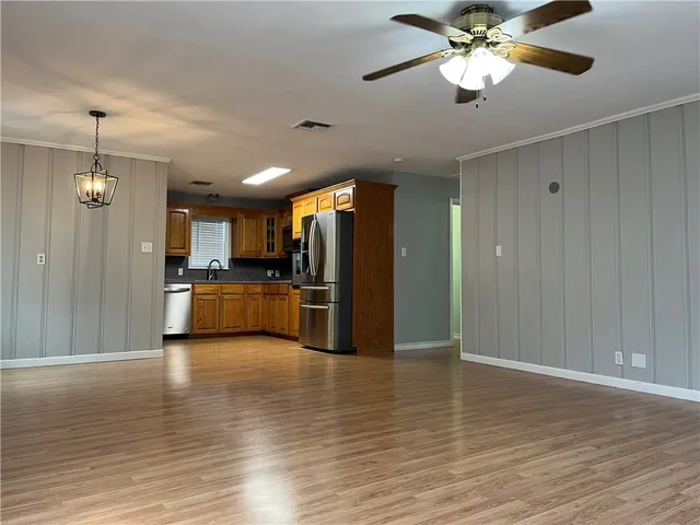 a view of a kitchen with a refrigerator a ceiling fan wooden floor and a kitchen view