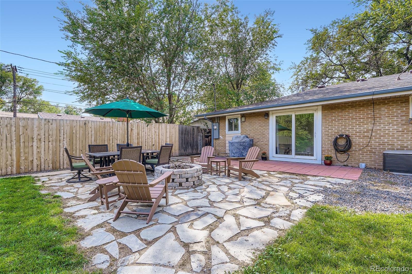 4720 Carr Street Wheat Ridge, CO 80033 - Photo 17 of 31 a view of a backyard with table and chairs under an umbrella