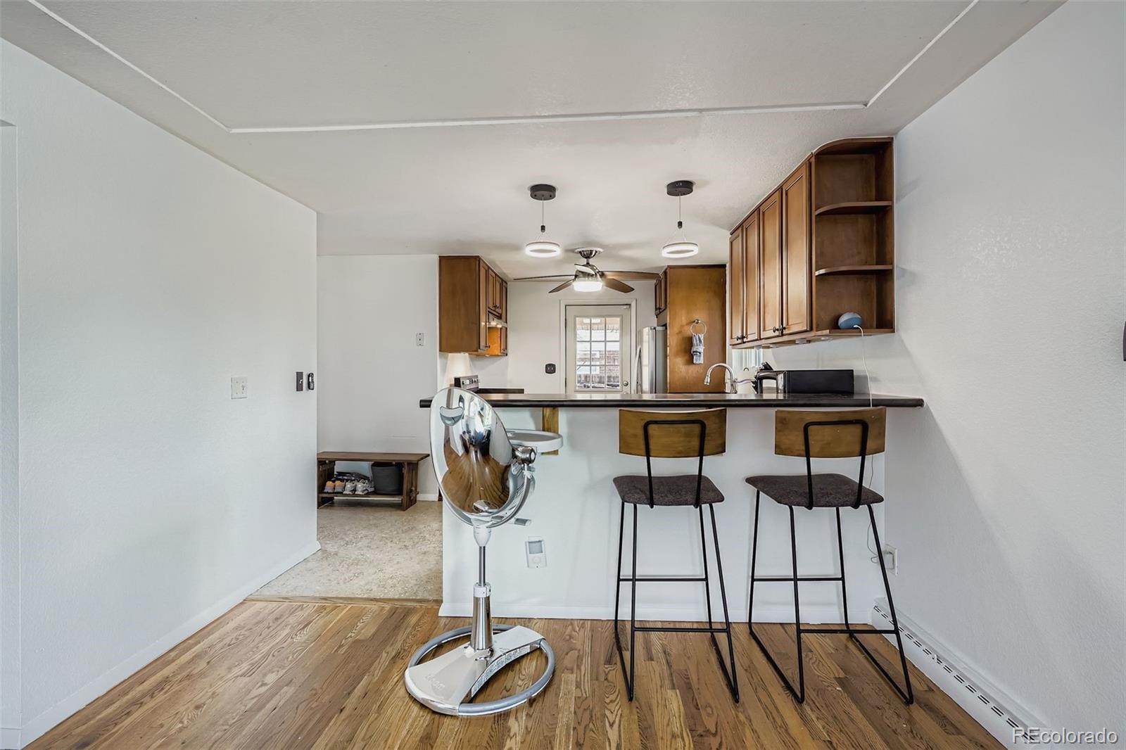 4720 Carr Street Wheat Ridge, CO 80033 - Photo 7 of 31 a kitchen with stainless steel appliances granite countertop a stove top oven a sink a dining table and chairs with wooden floor