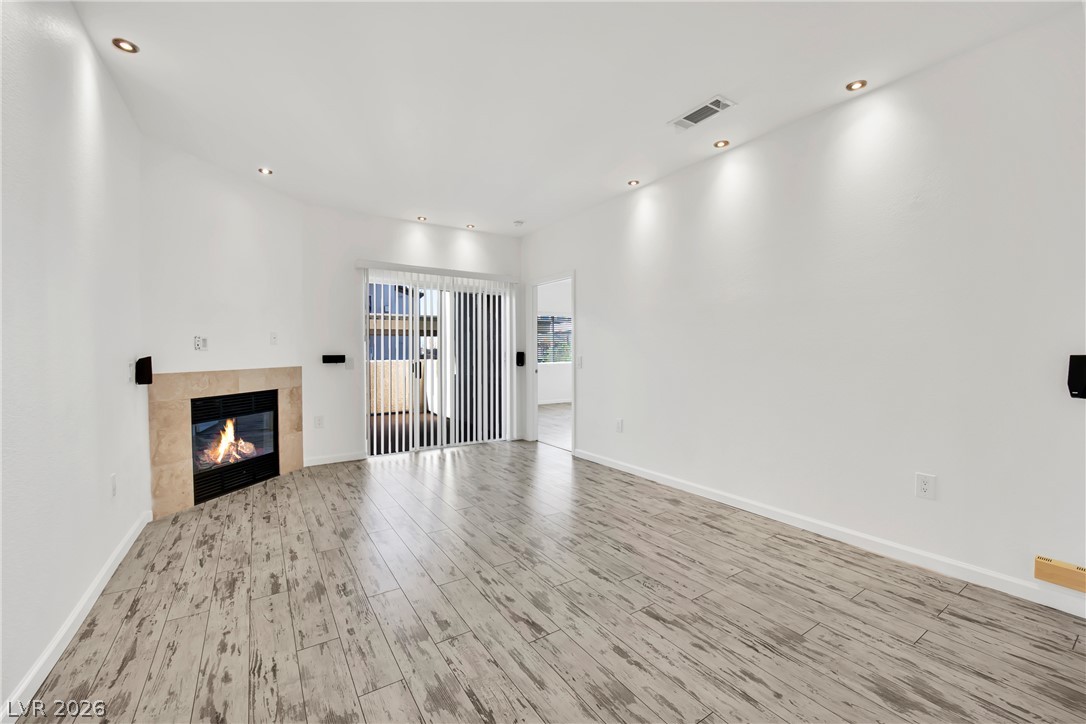 8725 West Flamingo Road, Unit 110 Las Vegas, NV 89147 - Photo 20 of 30 A well-lit living area with a cozy fireplace and convenient sliding glass doors to outdoor access.