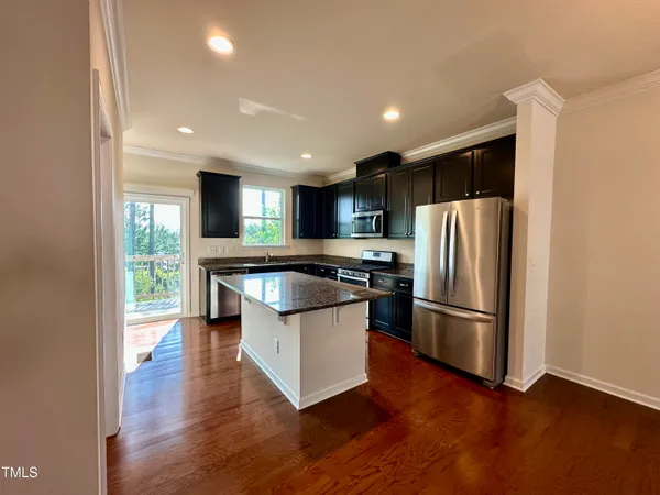 a kitchen with kitchen island a counter top space a refrigerator a sink and a dishwasher