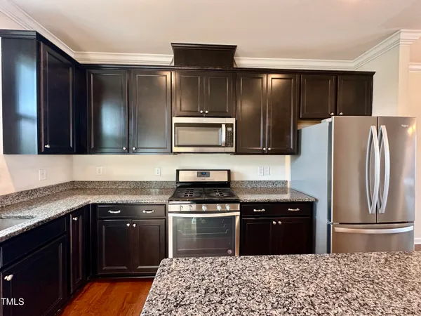 a kitchen with granite countertop a refrigerator and a stove top oven
