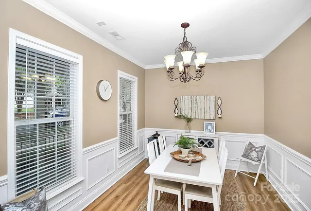 a dining room with wooden floor a chandelier a wooden table and chairs