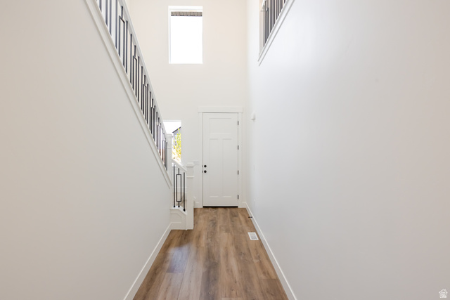 195 West Harmony Rdg Parkway, Unit 601 Mapleton, UT 84664 - Photo 20 of 23 Two-story entryway with wood-finish flooring, a white paneled door with dark hardware, and a staircase featuring dark metal balusters