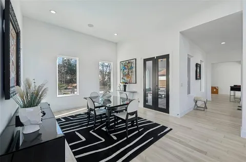 a large kitchen with stainless steel appliances kitchen island granite countertop a refrigerator a sink dishwasher a stove and a dining table with wooden floor