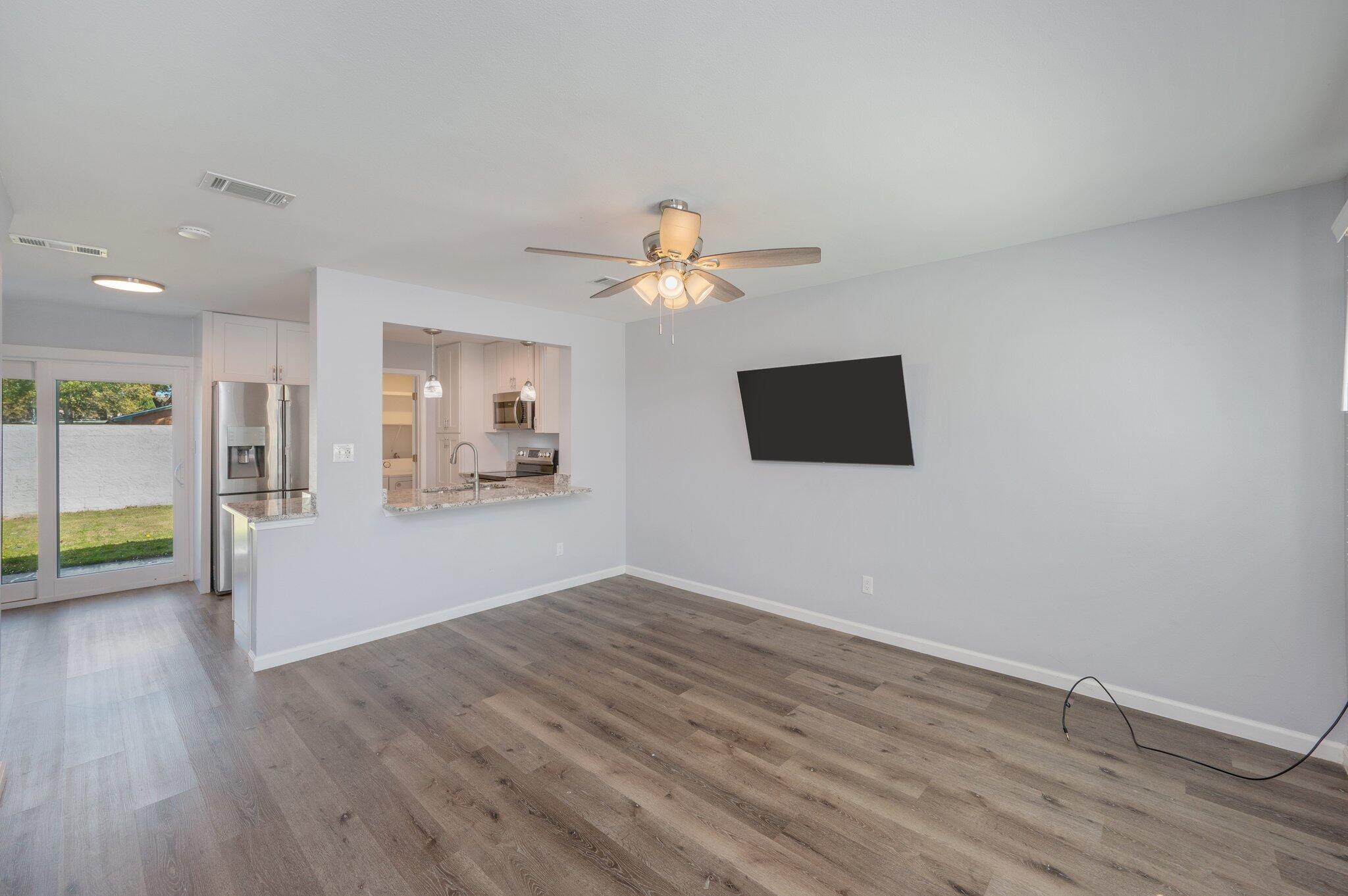 710 Legion Drive Destin, FL 32541 - Photo 6 of 29 a view of an empty room with wooden floor and a kitchen