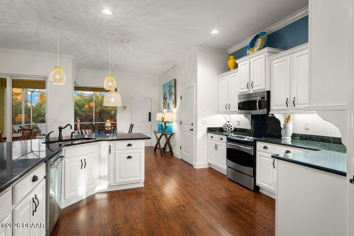 4767 Riverglen Boulevard Ponce Inlet, FL 32127 - Photo 31 of 60 a large kitchen with stainless steel appliances granite countertop a stove a sink dishwasher and a microwave oven with wooden floor