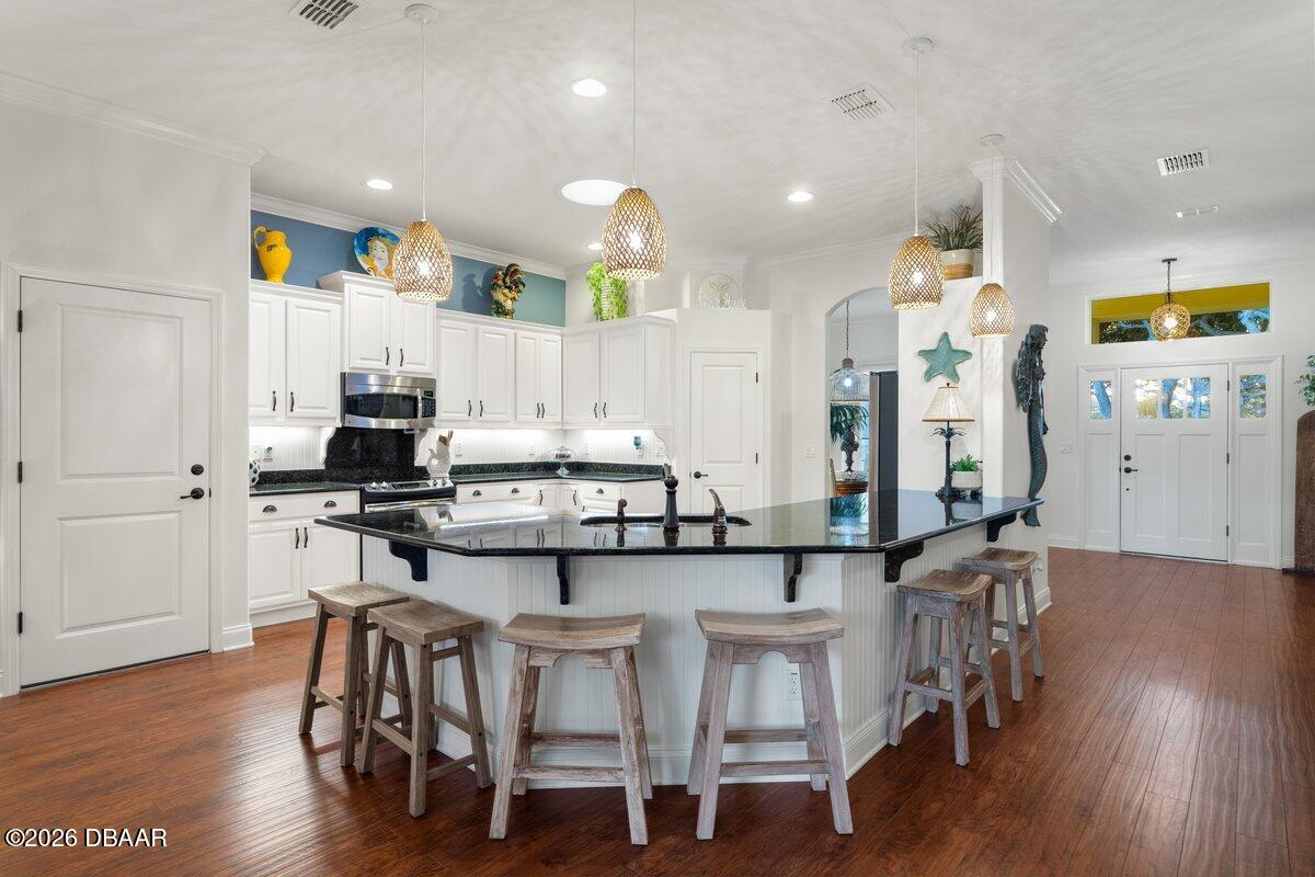 4767 Riverglen Boulevard Ponce Inlet, FL 32127 - Photo 37 of 60 a kitchen with stainless steel appliances kitchen island wooden floors and white cabinets