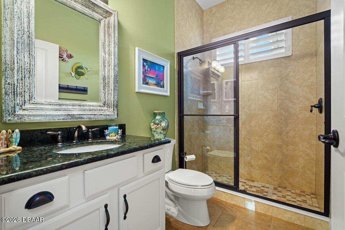 4767 Riverglen Boulevard Ponce Inlet, FL 32127 - Photo 52 of 60 a bathroom with a granite countertop sink mirror vanity and toilet